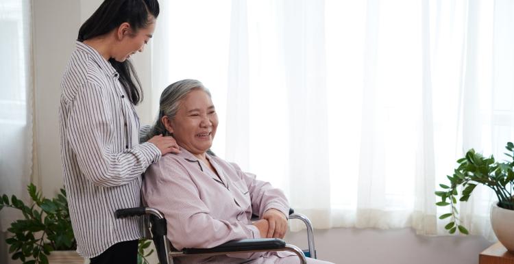  Caregiver talking to senior woman sitting in wheelchair