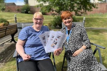Sharon Bell sits with Wendy Hadlington outside showcasing four easy read letters