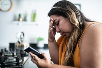 Worried mid adult woman using mobile phone in the living room at home