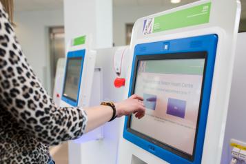 Womans hand using a digital touch screen to book in