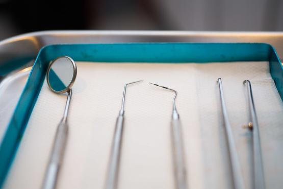 A set of dental tools are arranged on a tray.
