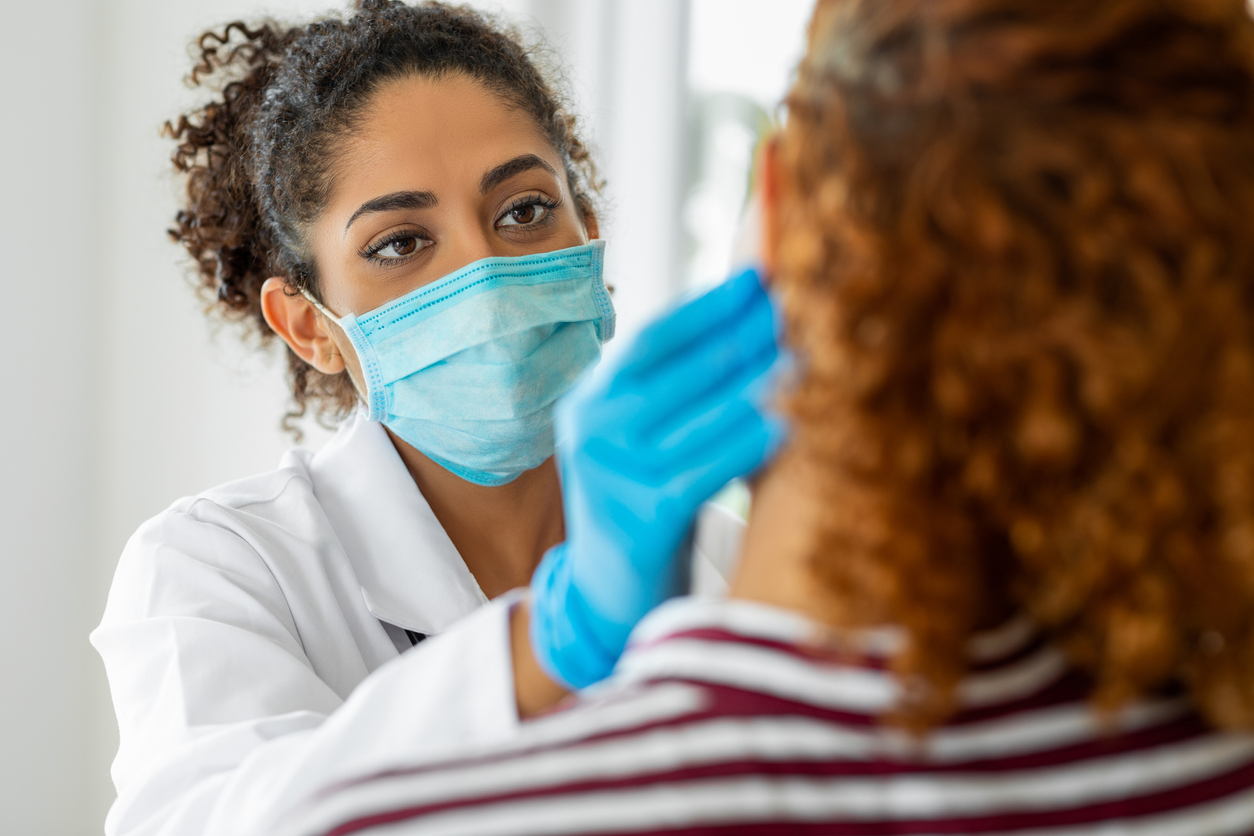 A female clinician is wearing a facemask. She is touching the face of a patient.