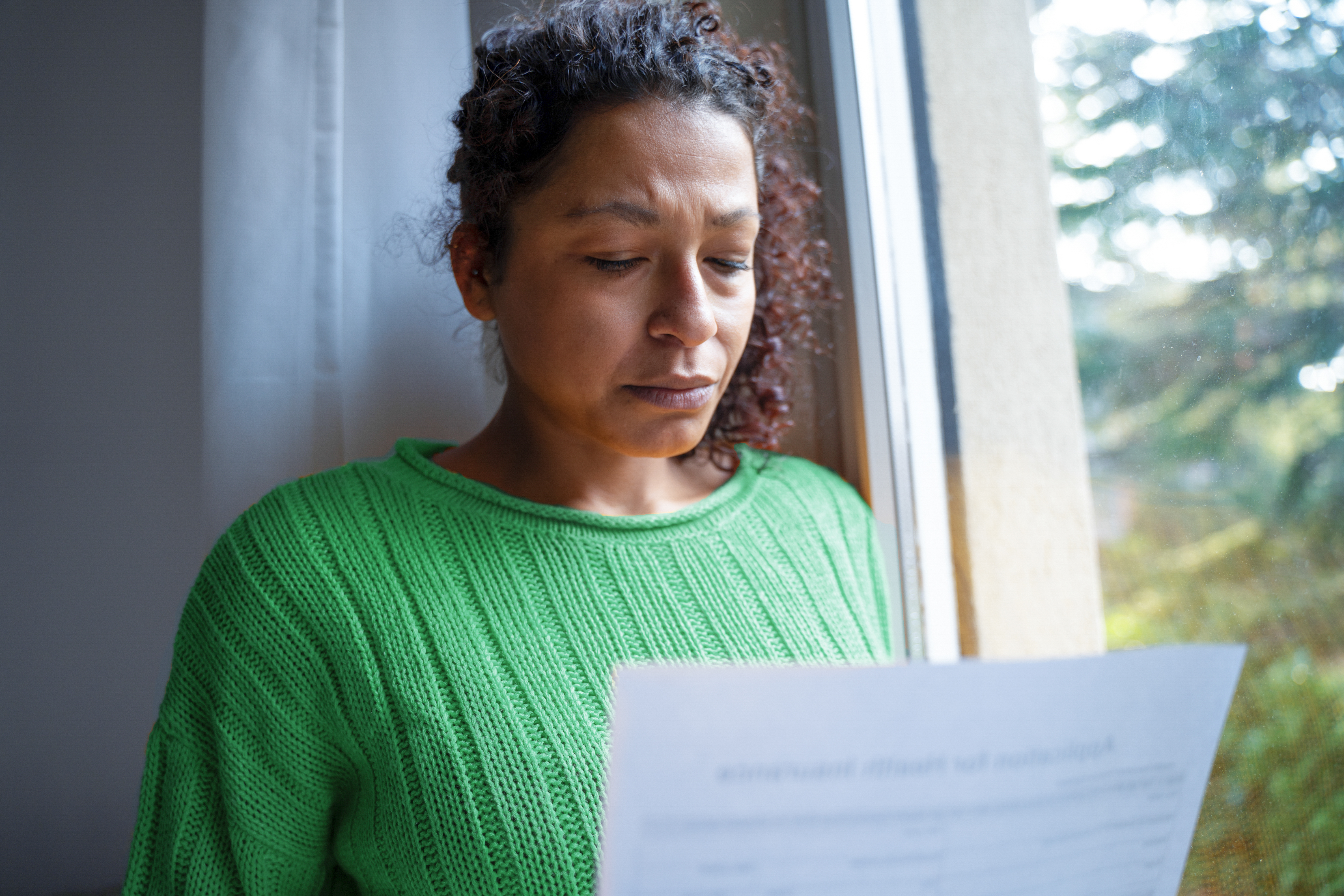 A middle-aged black woman getting bad news letter feeling worried