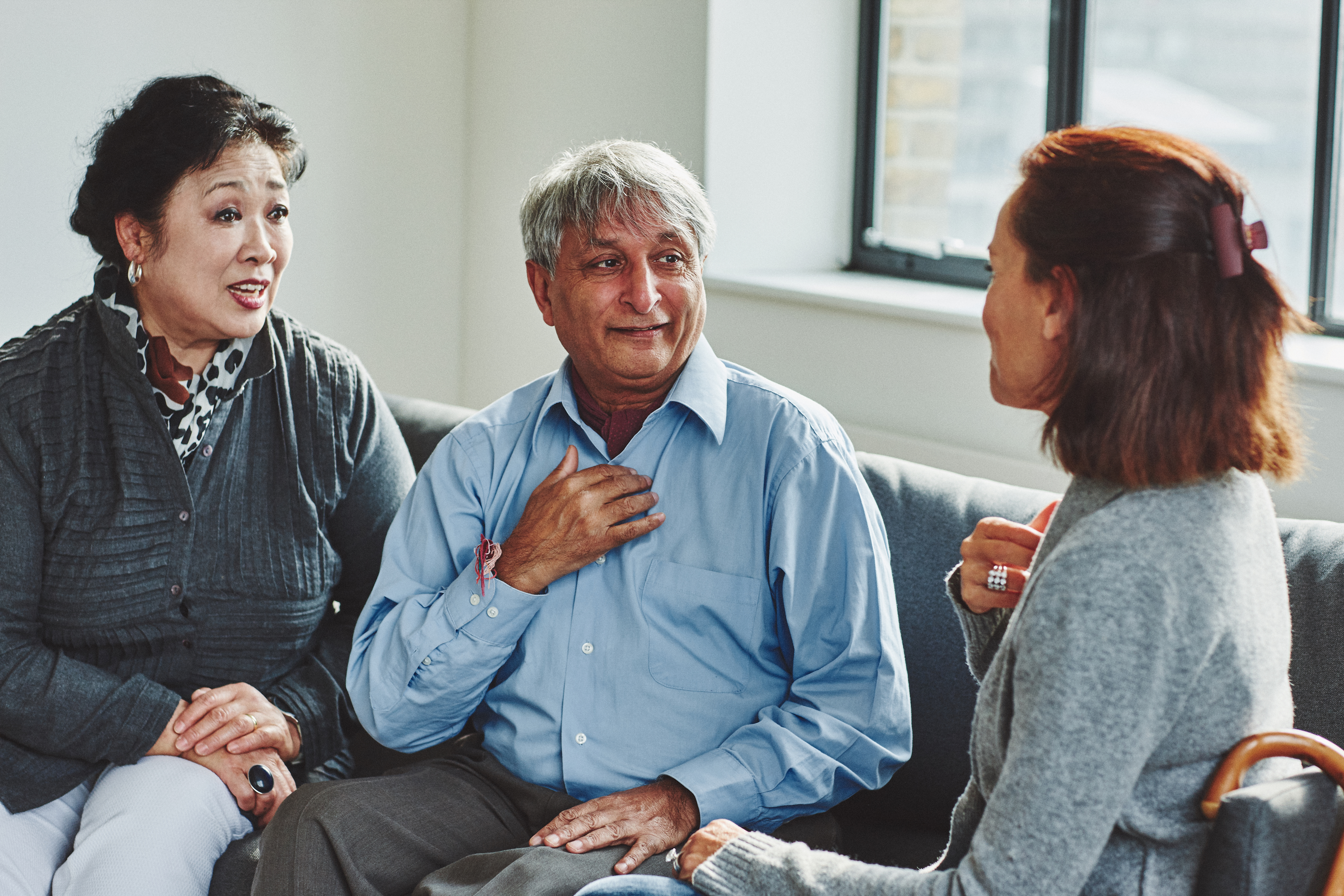 Older couple sit with GP in a room using sign language