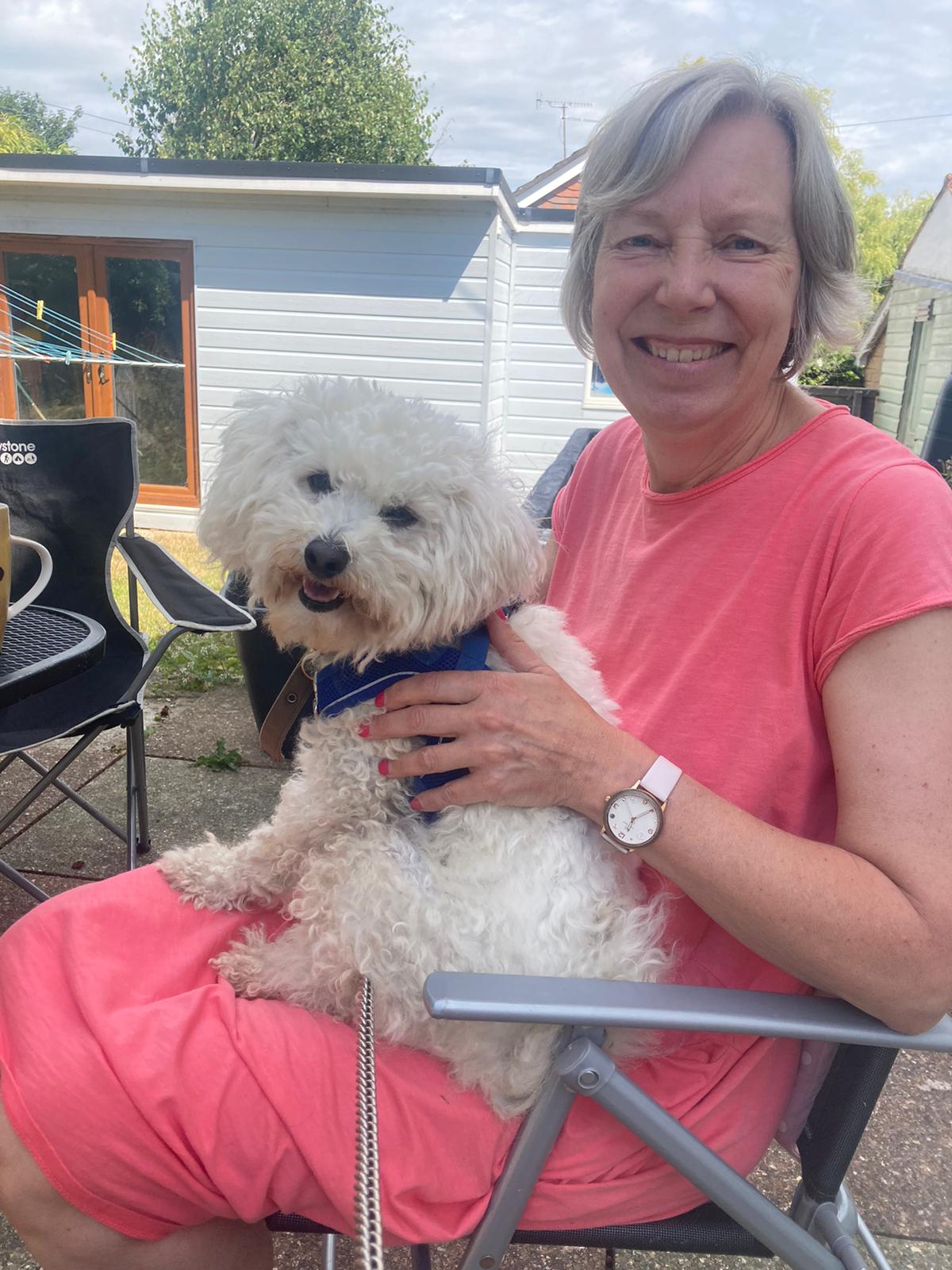 White woman aged 62 sitting and holding a puppy