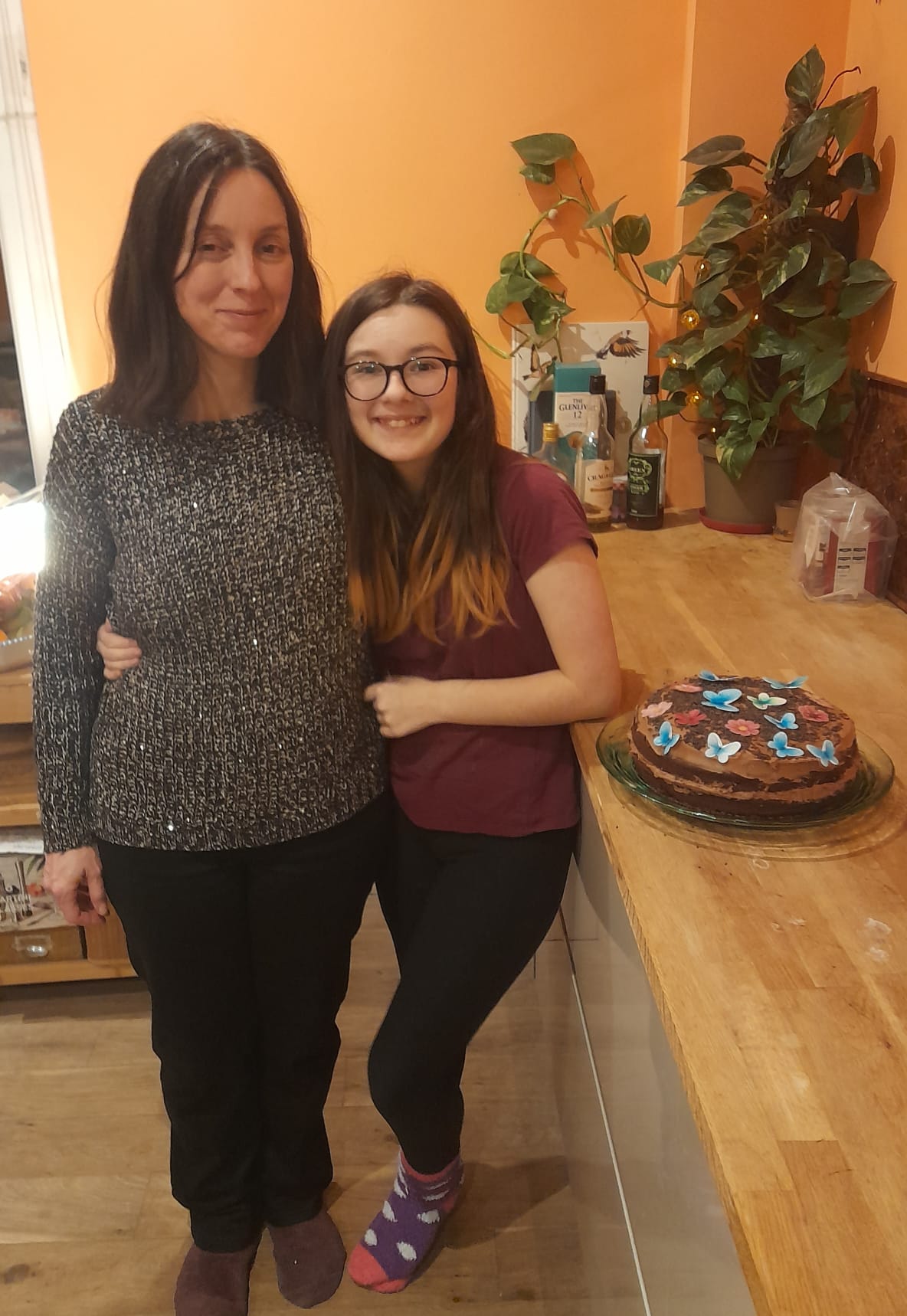 Emma and her daughter Chloe smiling at the camera in their house.