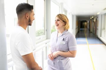 A man and a woman talking in a hospital corridor