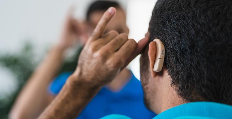 A man with a hearing aid communicates using sign language