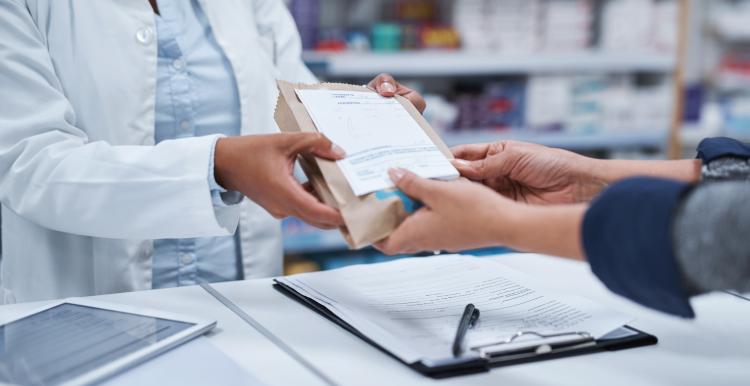 A pharmacist handing over a prescription to a patient