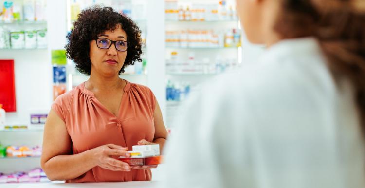 A customer is waiting at the checkout counter to pay for her medication