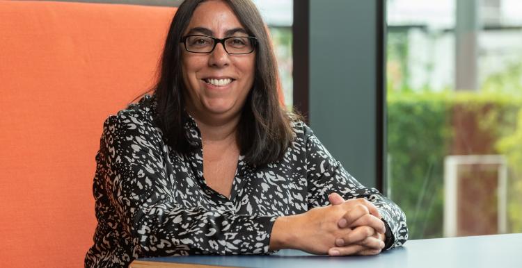 Chief Executive, Louise Ansari, sitting wearing black and white top and glasses.