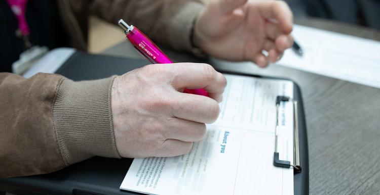Person filling in a form attached to a clipboard