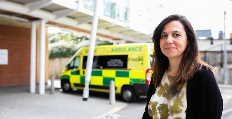 Woman smiling at the camera in front or an ambulance