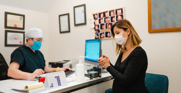 A woman in her local GP for her COVID-19 vaccine. Doctor and patient wear face masks. 