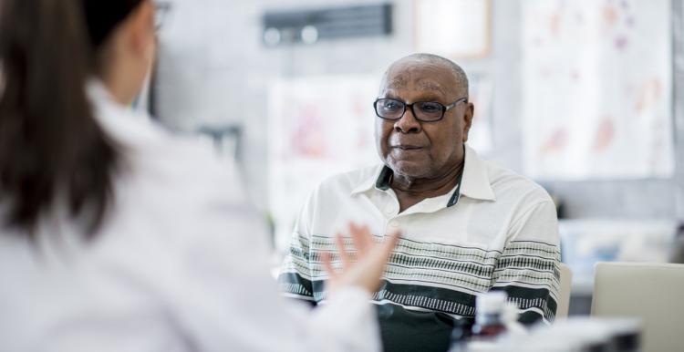 Older man listening to a female doctor talk to him