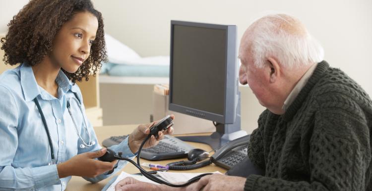 Female GP takes blood pressure of older man