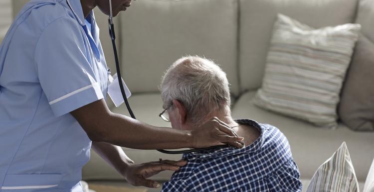 Female nurse using a stethoscope on a male patient