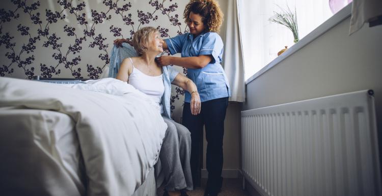 A carer helping a woman out of bed