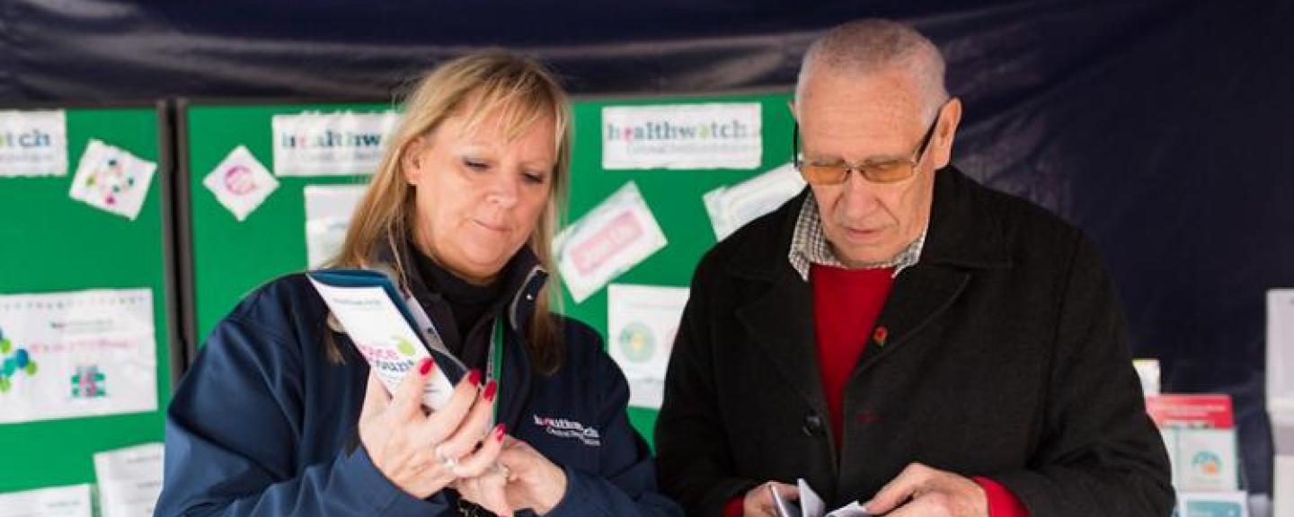 Man and woman looking at Healthwatch leaflets