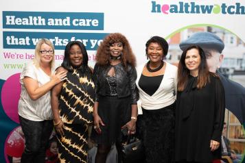 Five women standing in front of a Healthwatch background
