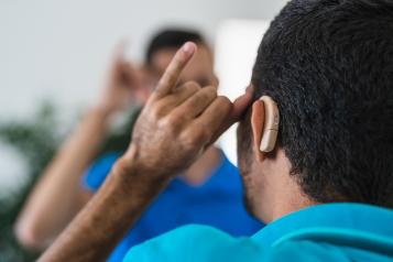A man with a hearing aid communicates using sign language
