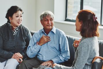 A young woman sits with an elderly couple having a conversation