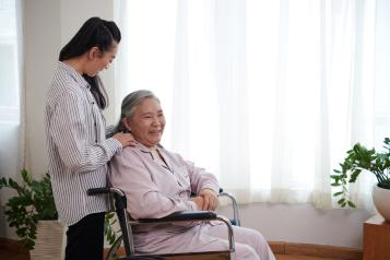  Caregiver talking to senior woman sitting in wheelchair