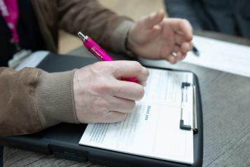 Person filling in a form attached to a clipboard