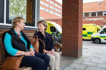 Two women sitting outside an emergency department