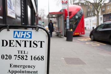 A sign on a street gives information about an NHS dentist