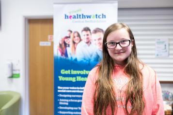Young girl in front of Healthwatch sign