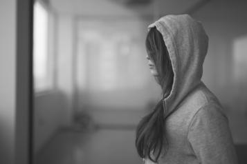 A black and white image of a teenage girl in a hood