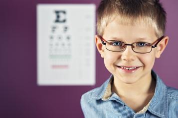 front picture of child with glassed and the eye test board on the background
