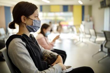 Women waiting in a hospital wearing a mask.