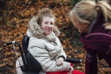 Young woman wearing a winter coat. She is sitting in a wheelchair. 