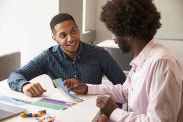 two men sitting at a desk completing paperwork