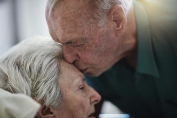 Elderly man kissing his wife on the forehead