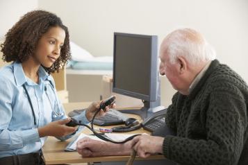 Female GP takes blood pressure of older man