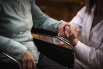 A carer holding a woman's hand