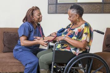 A nurse taking the blood pressure of a woman in a wheelchair