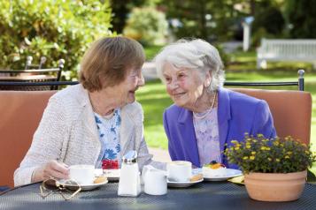 Two elderly women laughing over tea