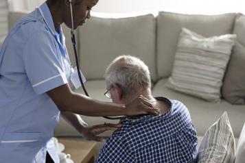 nurse performing health check on old male patient