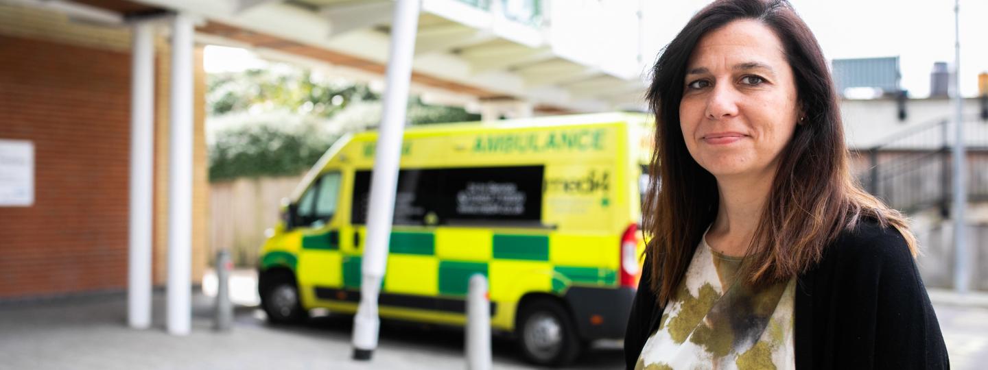Woman smiling at the camera in front or an ambulance