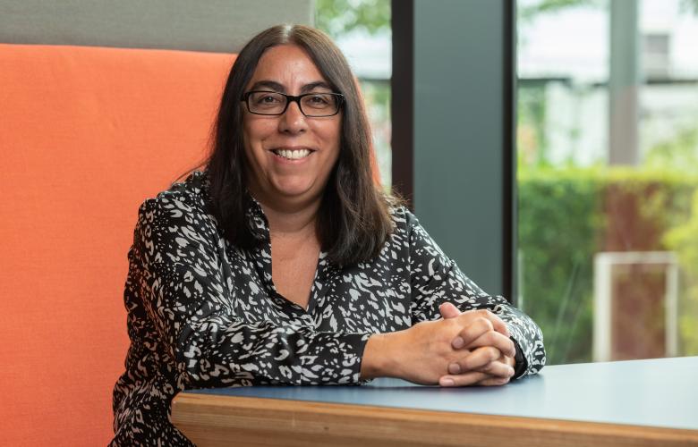 Chief Executive, Louise Ansari, sitting wearing black and white top and glasses.